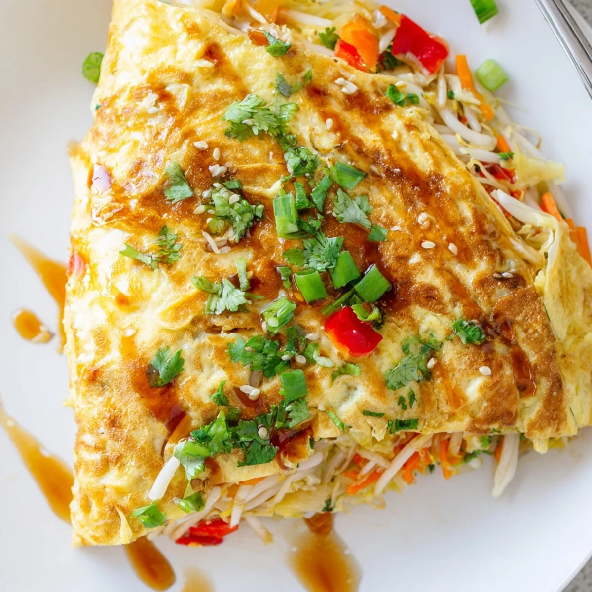Fluffy Chinese omelette served hot on a plate with a chili sauce drizzle