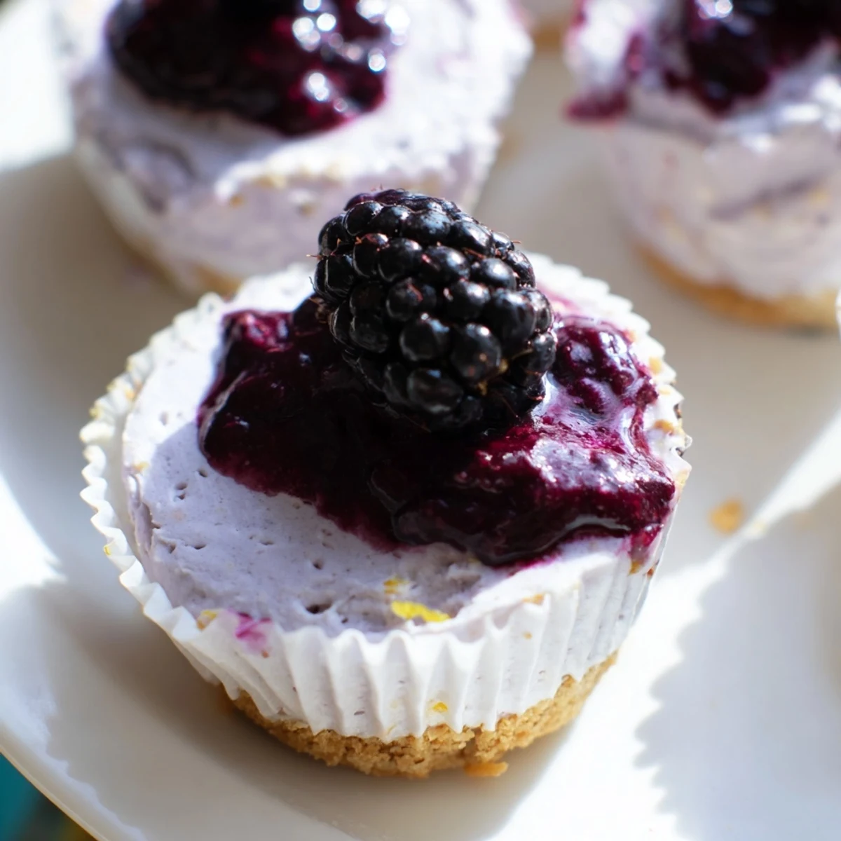Mini blackberry lavender cheesecakes topped with glossy purple berry sauce on graham crusts