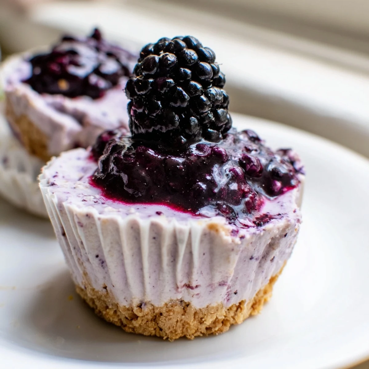 Individual blackberry lavender cheesecakes with lavender buds and jewel toned blackberry compote drizzle