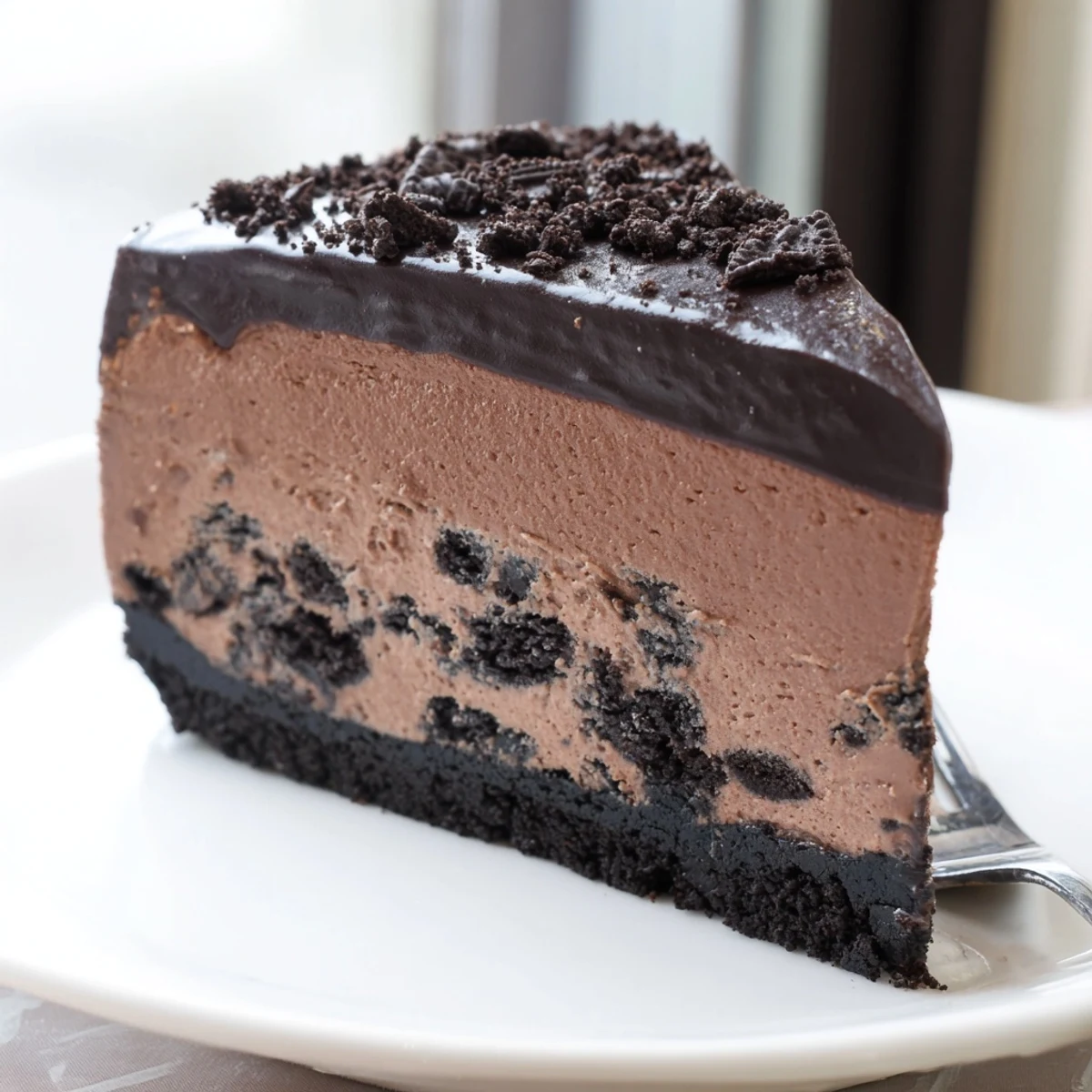 Velvety Oreo chocolate cheesecake topped with crushed cookies and drizzled chocolate ganache