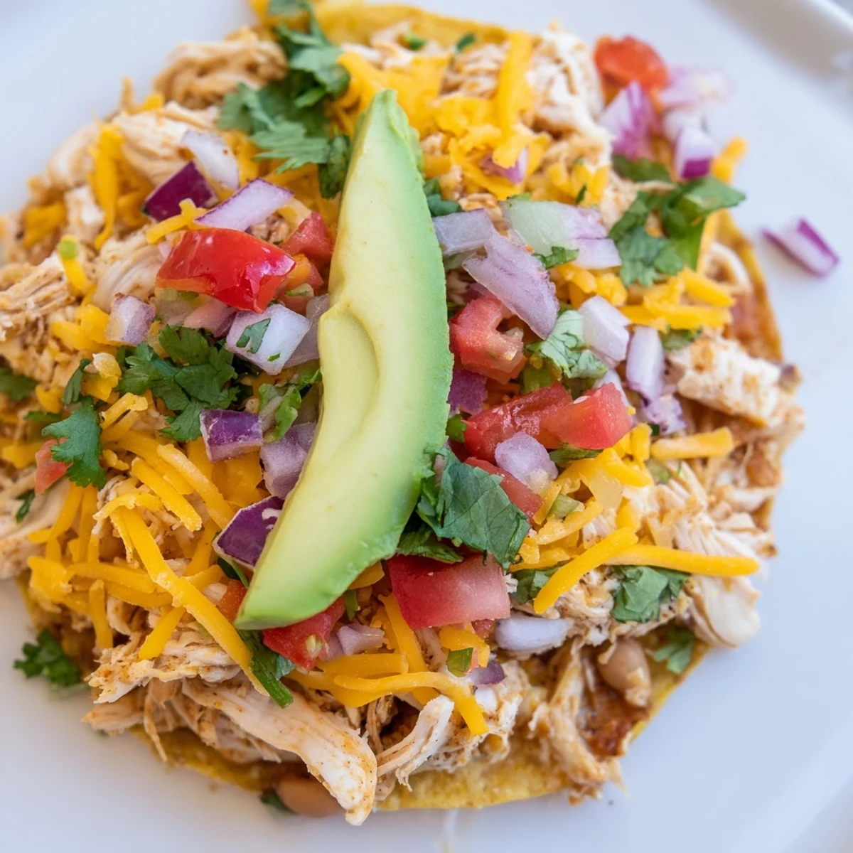 Vibrant Chicken Tostadas topped with fresh lettuce, cheese, and creamy sour cream layers.  