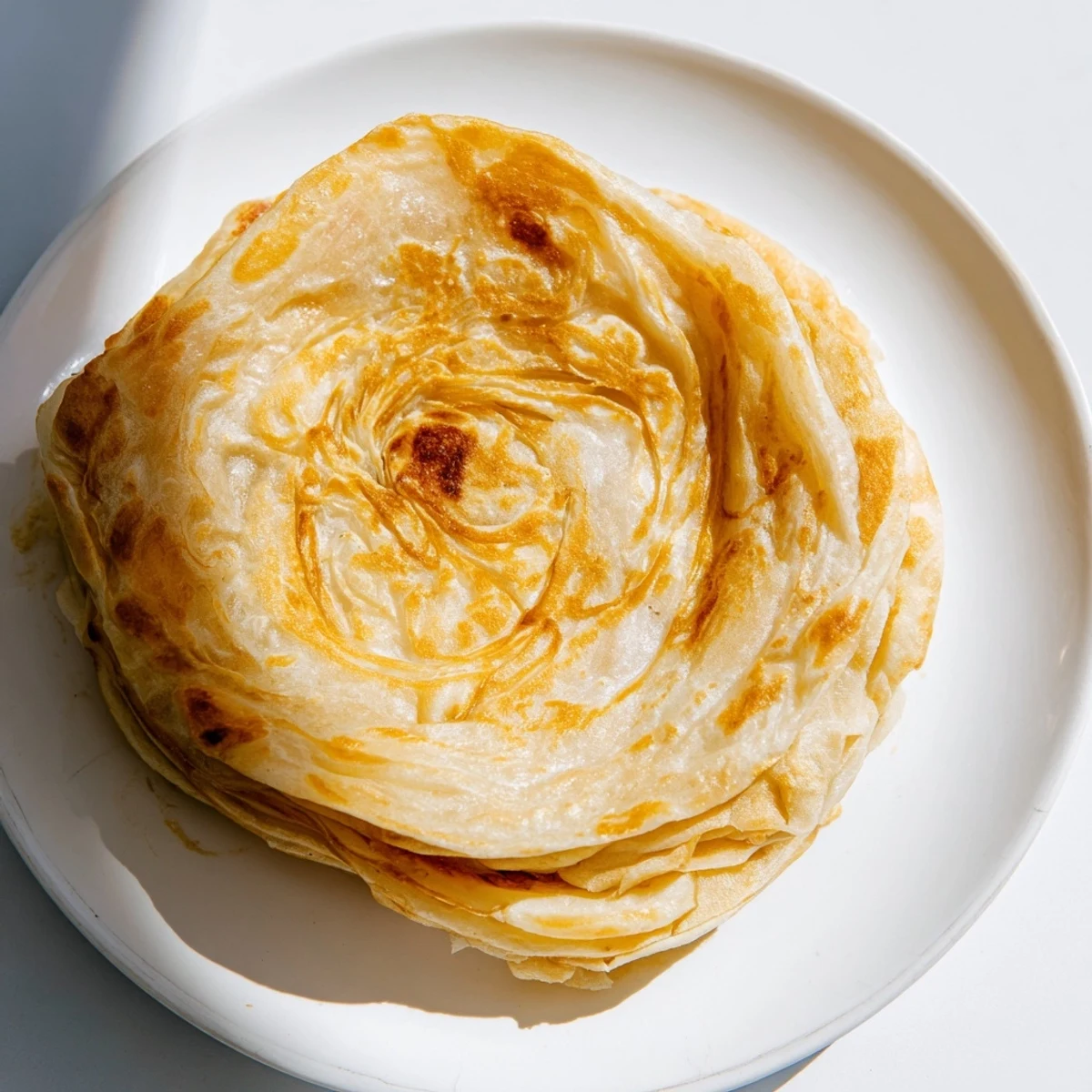 Golden flaky Roti Canai flatbread served with aromatic curry for dipping  