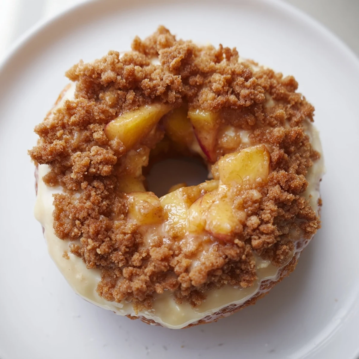 Golden peach cobbler cheesecake donuts topped with crunchy crumbs and sweet glaze  