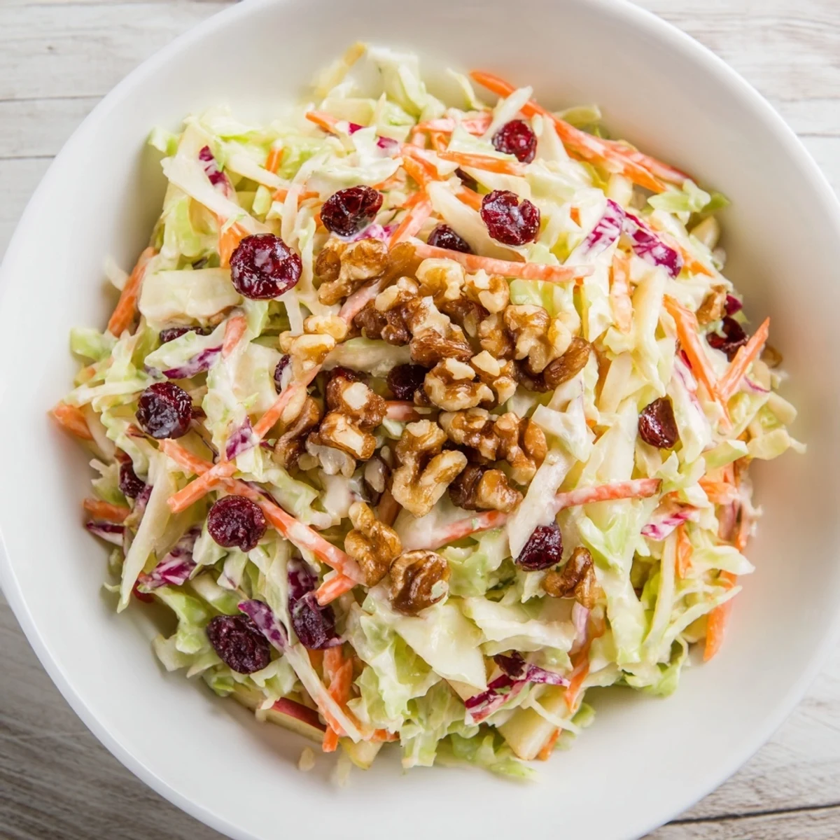 Creamy Cranberry Apple Coleslaw topped with crunchy walnuts and fresh green onions.