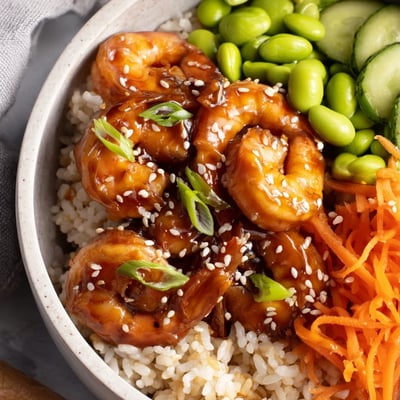 Vibrant teriyaki shrimp rice bowls topped with crisp veggies and sesame seeds.  