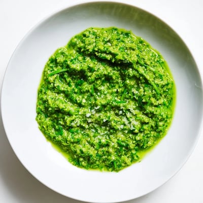 Creamy garlic scape pesto spread on crusty bread, garnished with pine nuts.  