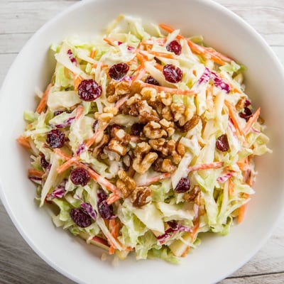 Creamy Cranberry Apple Coleslaw topped with crunchy walnuts and fresh green onions.
